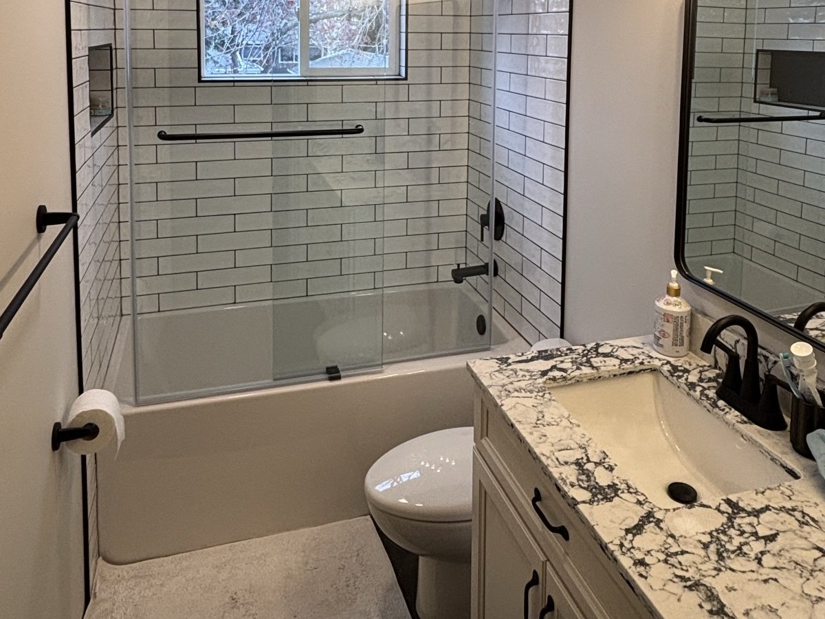 Full bathroom renovation with white subway tile, marble vanity, and matte black fixtures