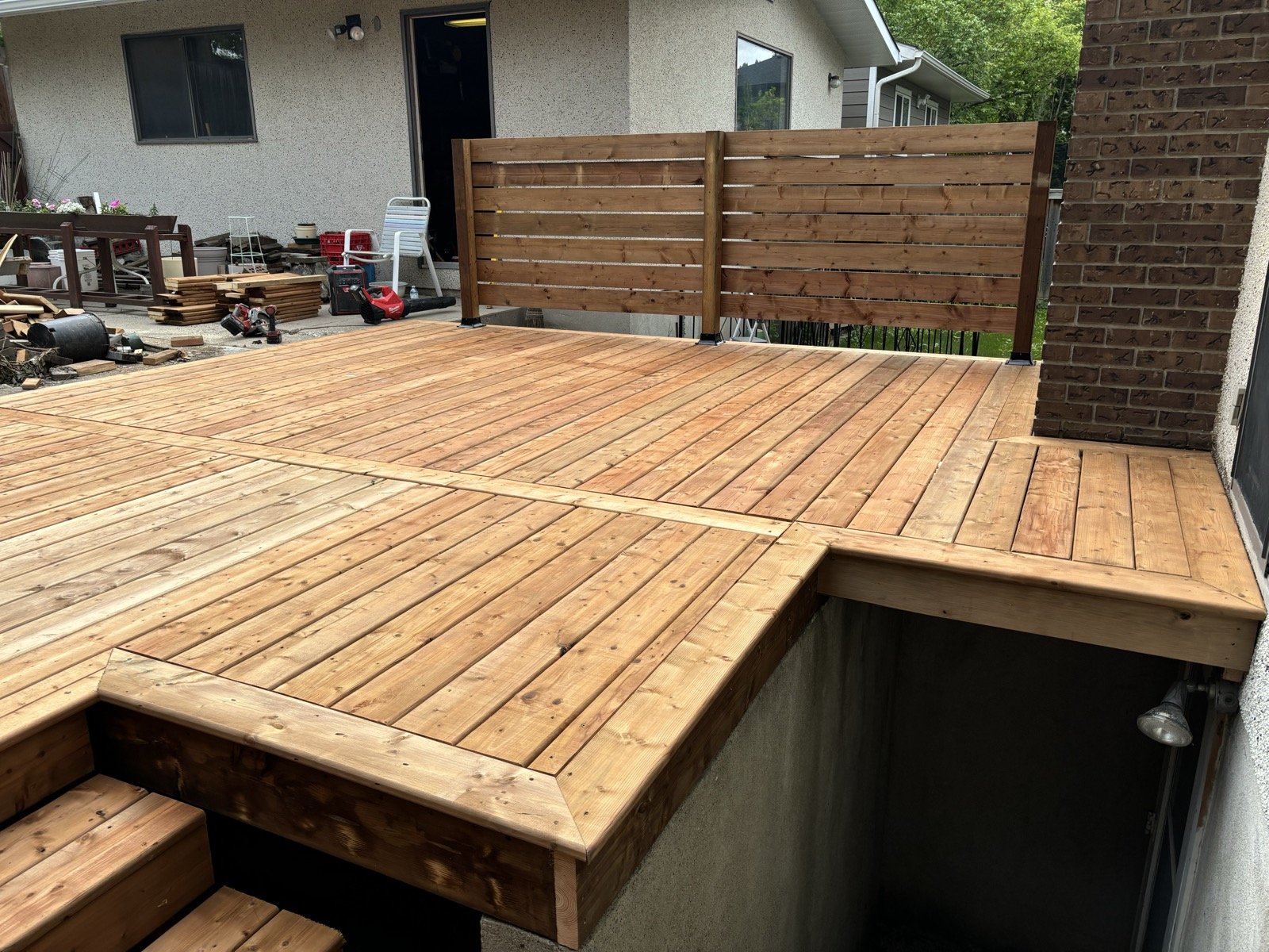 Large cedar deck with wrap-around bench seating and a horizontal slat privacy screen