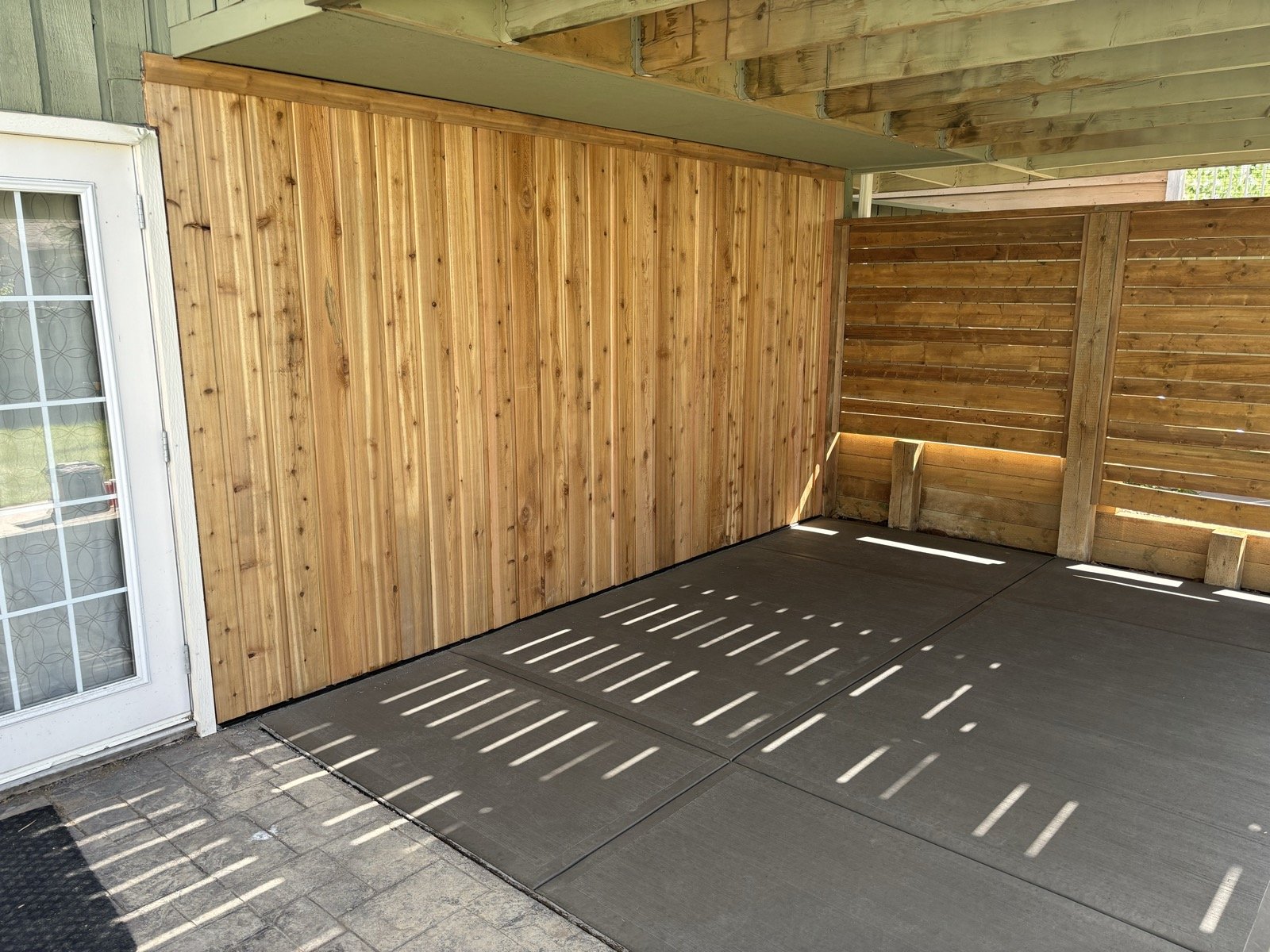 Smooth-finished concrete slab under a deck with a cedar feature wall