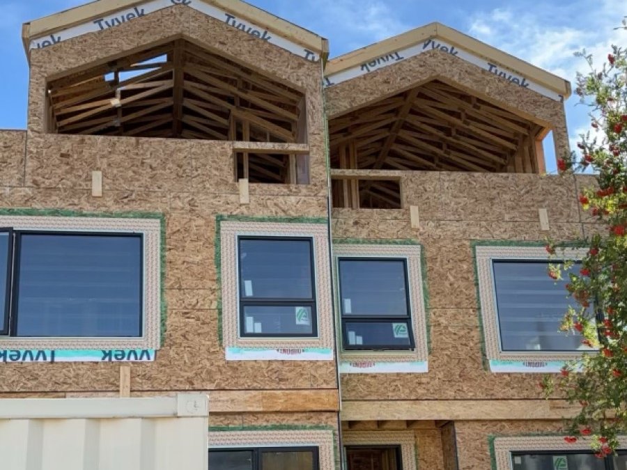 Two-storey custom home under construction, showing framed dormers and window openings